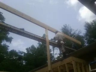 Carpenter setting a ridge beam over a new addition frame — Ice Dam Removal by Roofing Brothers in Fort Stewart