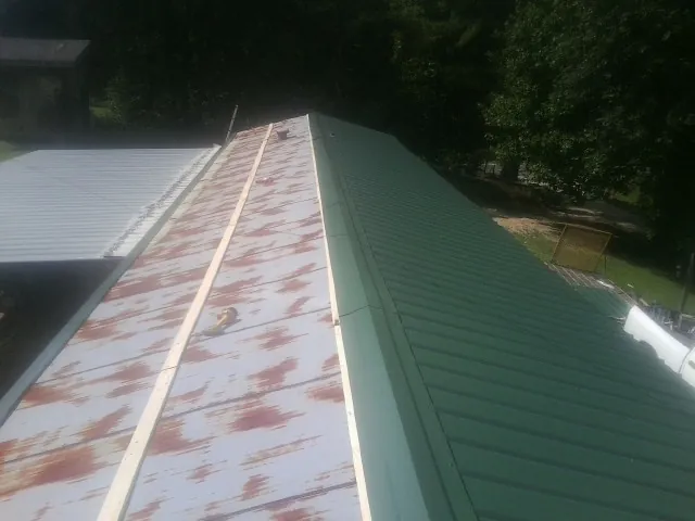 Old rusted panels beside newly installed green metal roofing — Wind Damage Roof Repair by Roofing Brothers in Fort Stewart