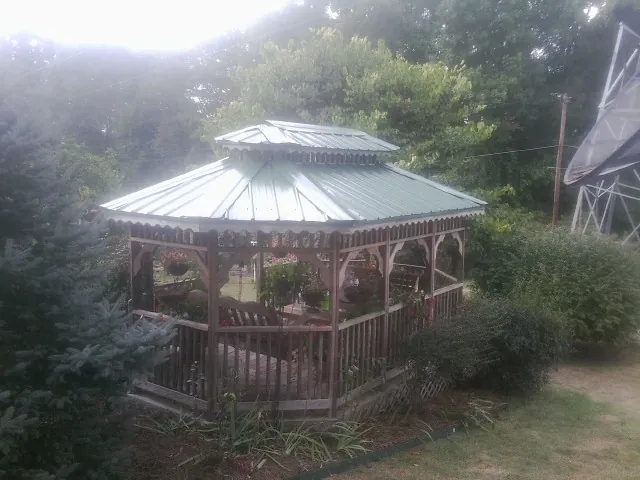 Green metal roof on a backyard gazebo surrounded by garden beds in Fort Stewart