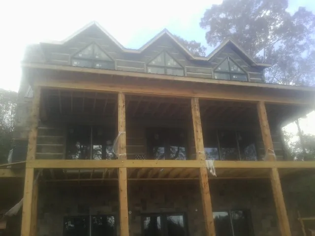 Dormers and porch framing on a large log home under construction — Roof Coating work by our crew in Fort Stewart
