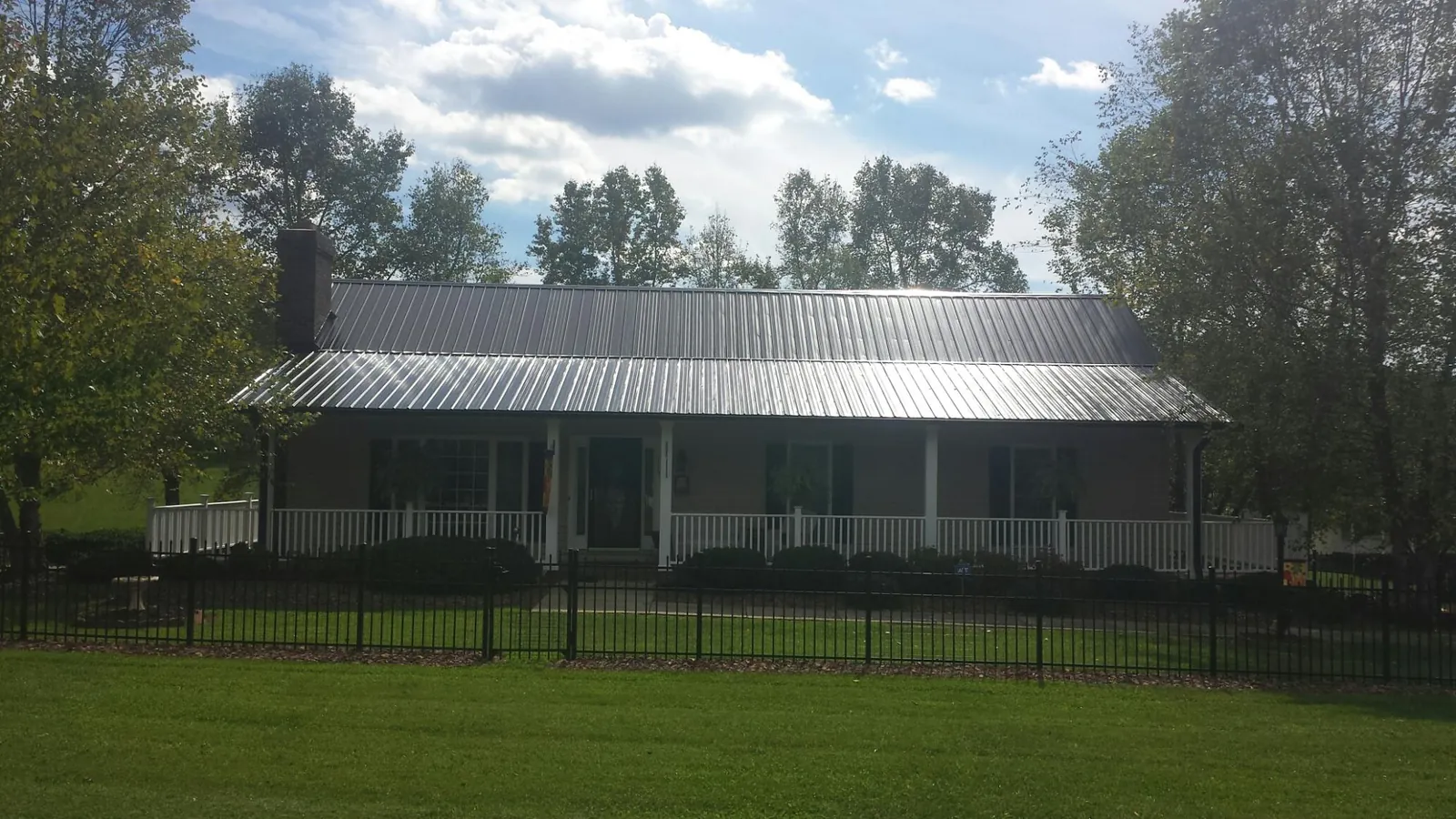 Gray metal roof on a brick ranch with a full width front porch — Gutter Guard Installation work by our crew in Fort Stewart