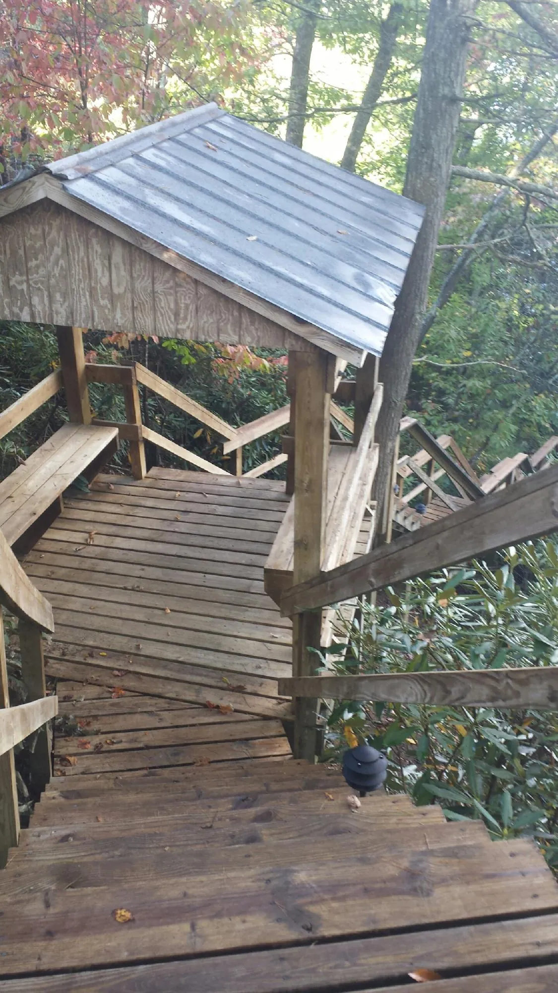 Metal roofed shelter over wooden steps on a wooded walkway — Skylight Repair & Installation work by our crew in Fort Stewart