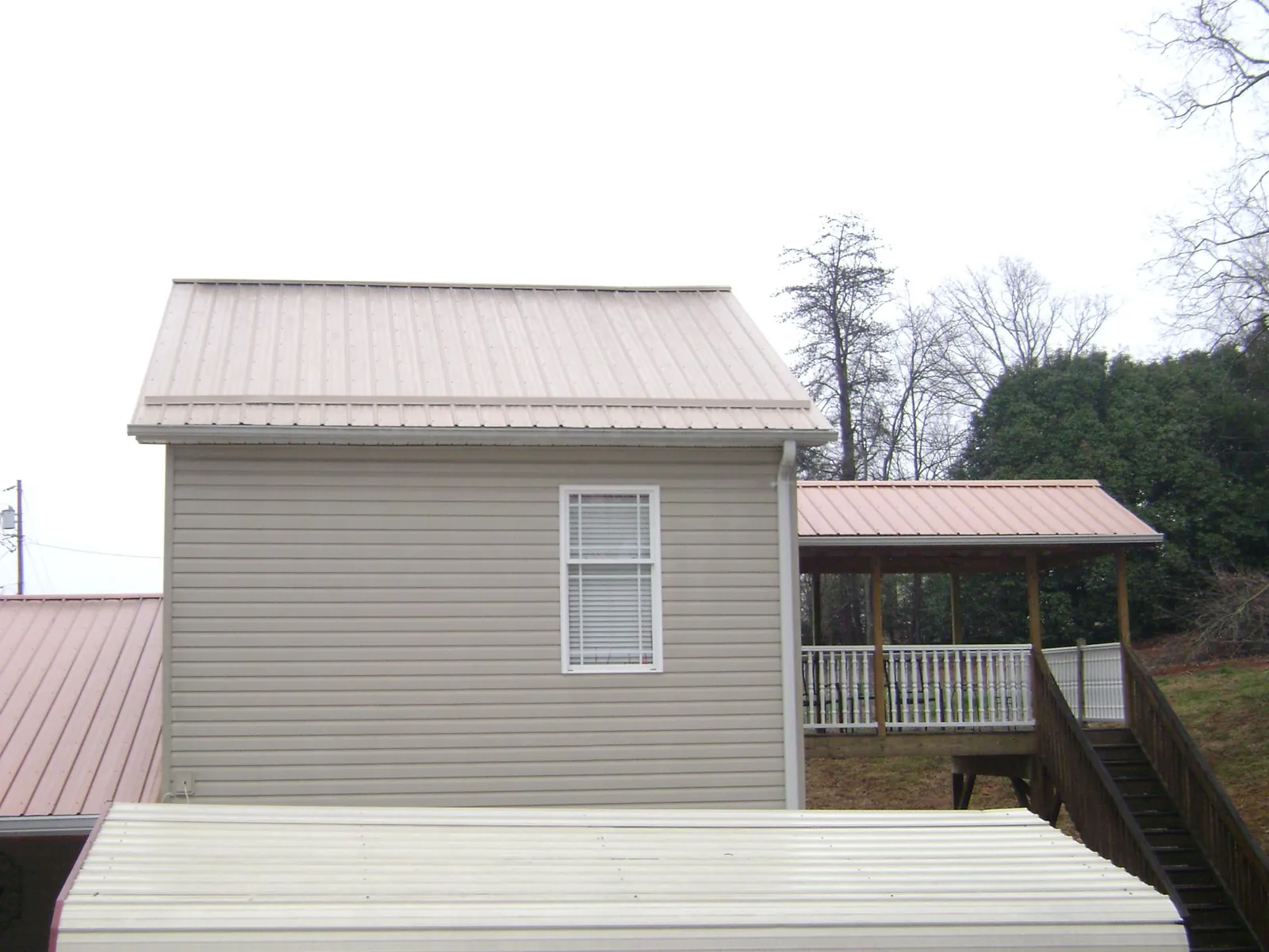 Tan metal roofs on a two story addition and attached porch, from a Roof Replacement job in Fort Stewart