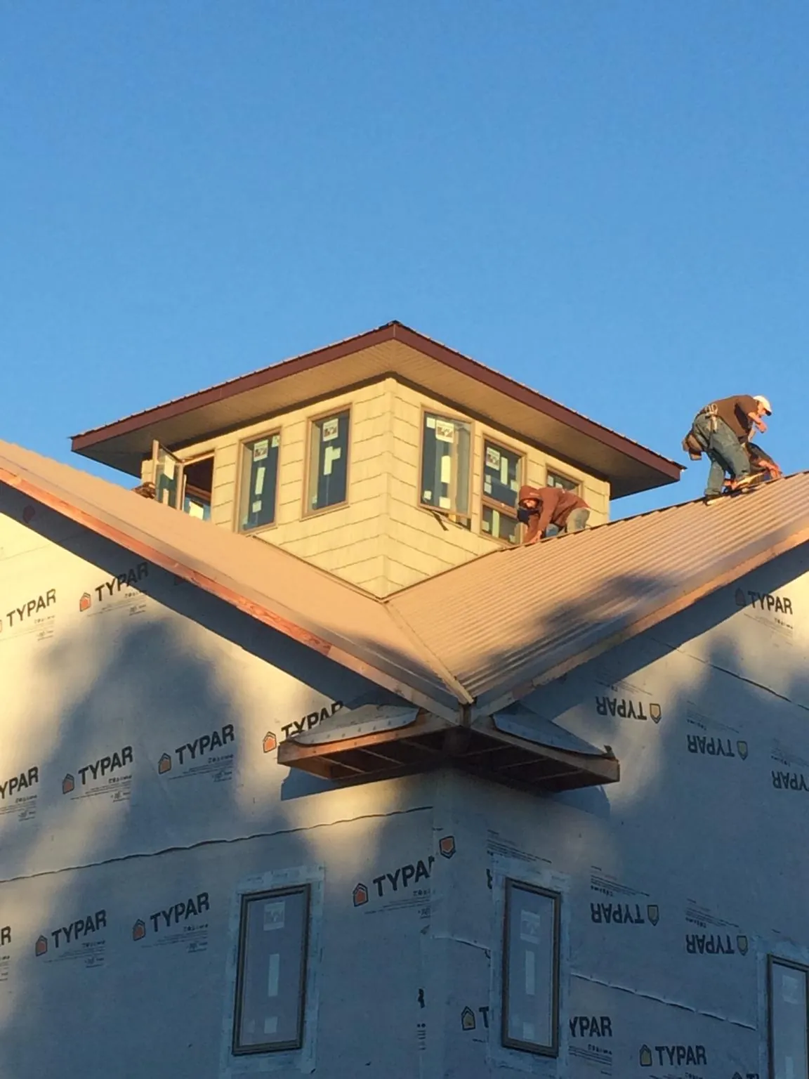 Roofers working around a rooftop cupola on a new metal roof at sunset — Roof Waterproofing in Fort Stewart by Roofing Brothers